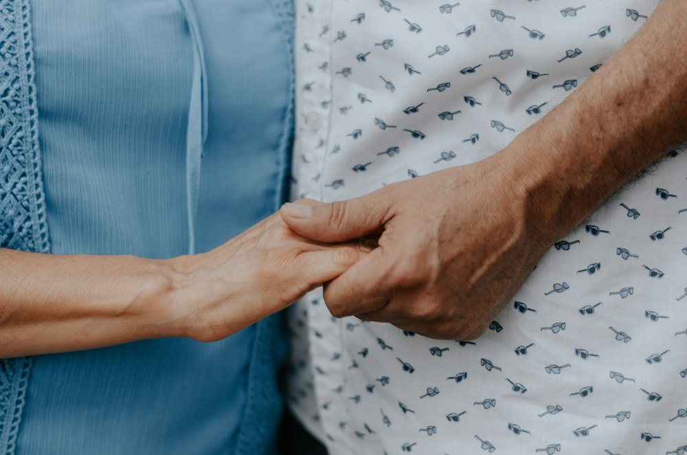 Eine jüngere Hand hält die Hand eines älteren Menschen